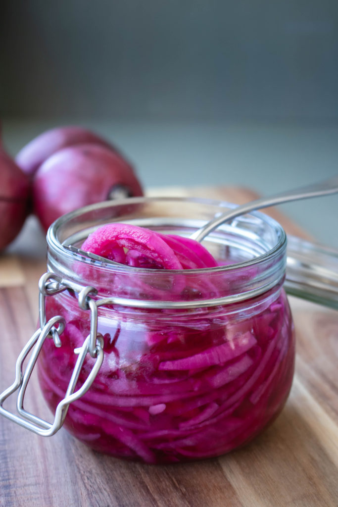 Pickled Red Onions in a jar with a fork.