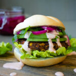 The burger in a bun served with sauce and veggies.