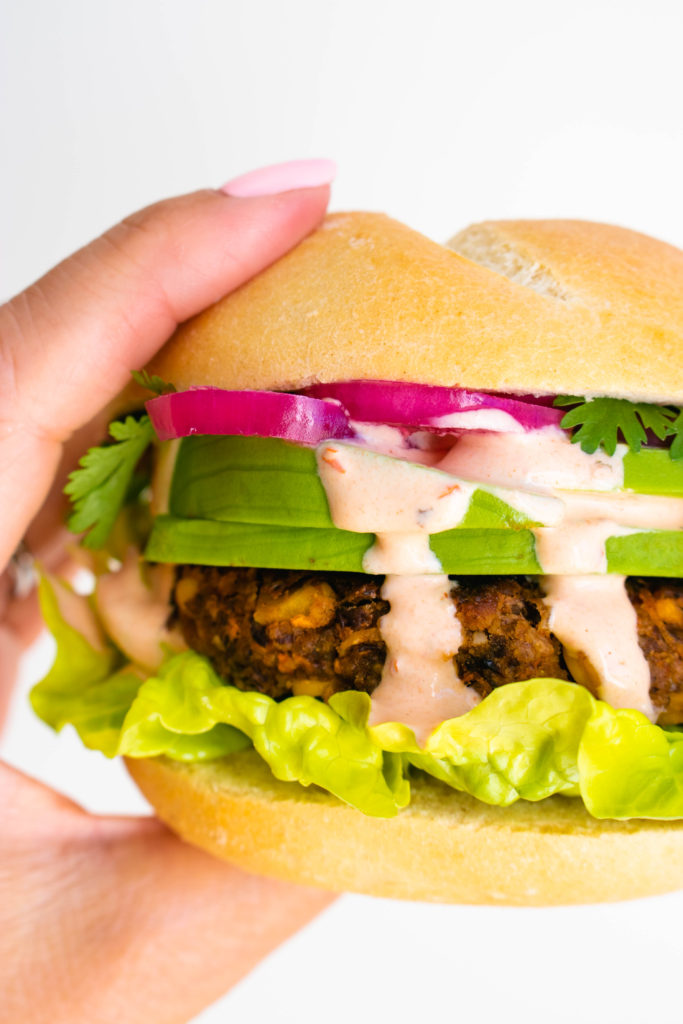 The burger in a bun with toppings and sauce.