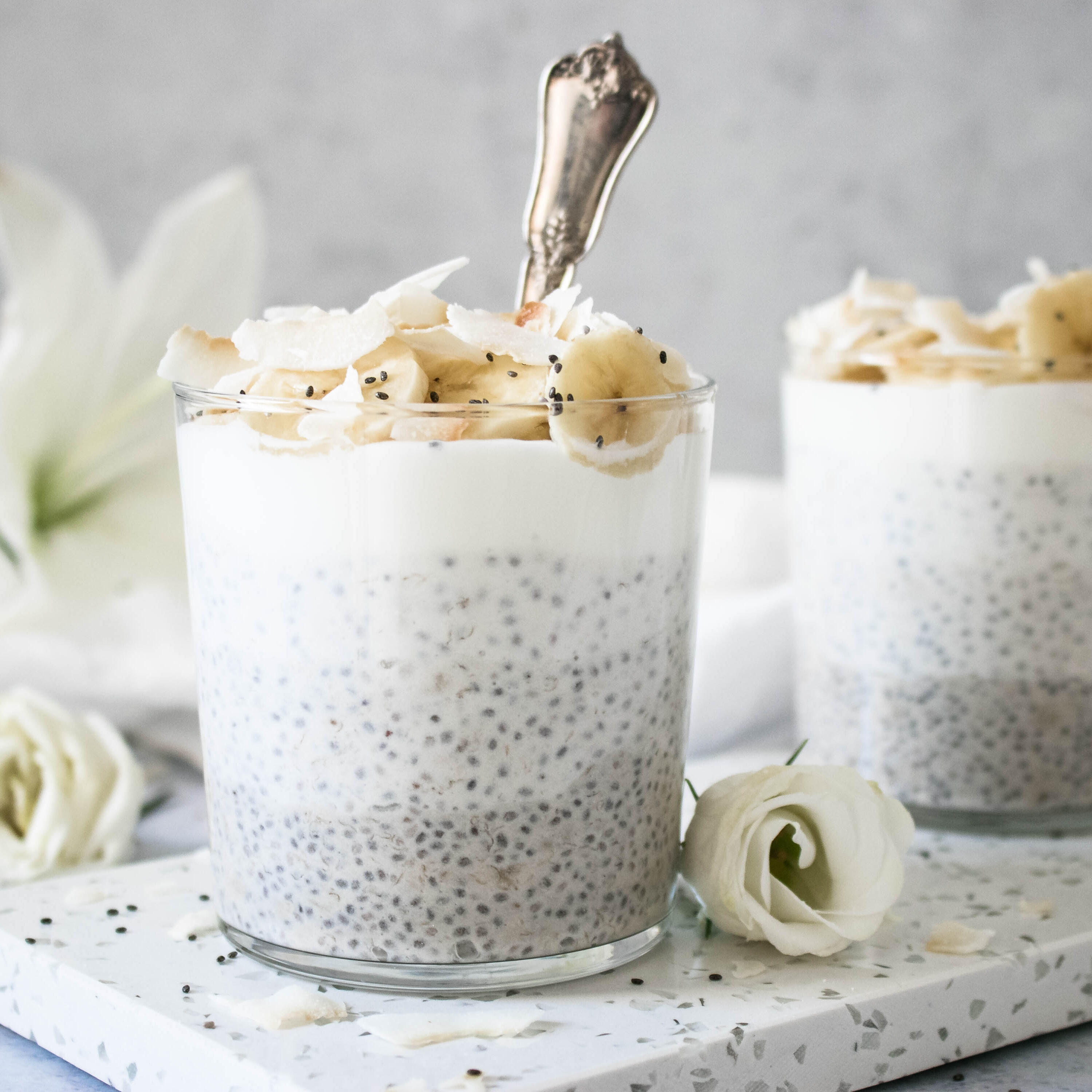 Creamy Coconut Chia Pudding served in a glass topped with banana and coconut.