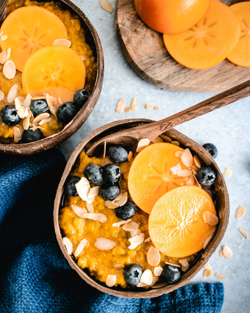 Persimmon Oatmeal served in a bowl topped with fresh persimmons, blueberries and almonds.