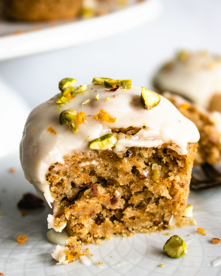 Mini Vegan Orange and Pistachio cake topped with a glaze, chopped pistachios and orange zest.
