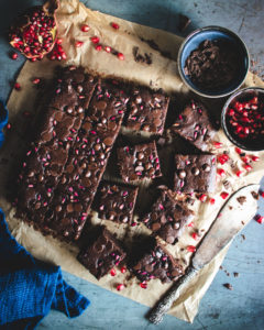 Vegan Pomegranate Brownies cut into pieces with fresh pomegranate seeds on the side.