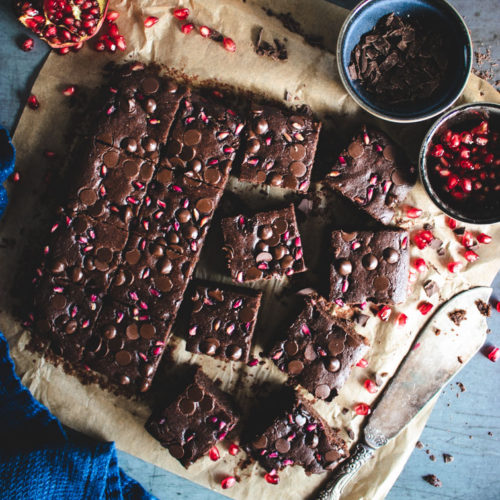 Vegan Pomegranate Brownies cut into pieces with fresh pomegranate seeds on the side.