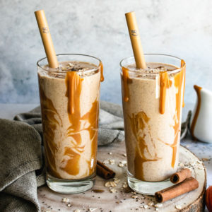 Apple Pie Smoothie served with an easy vegan caramel sauce in 2 tall glasses.