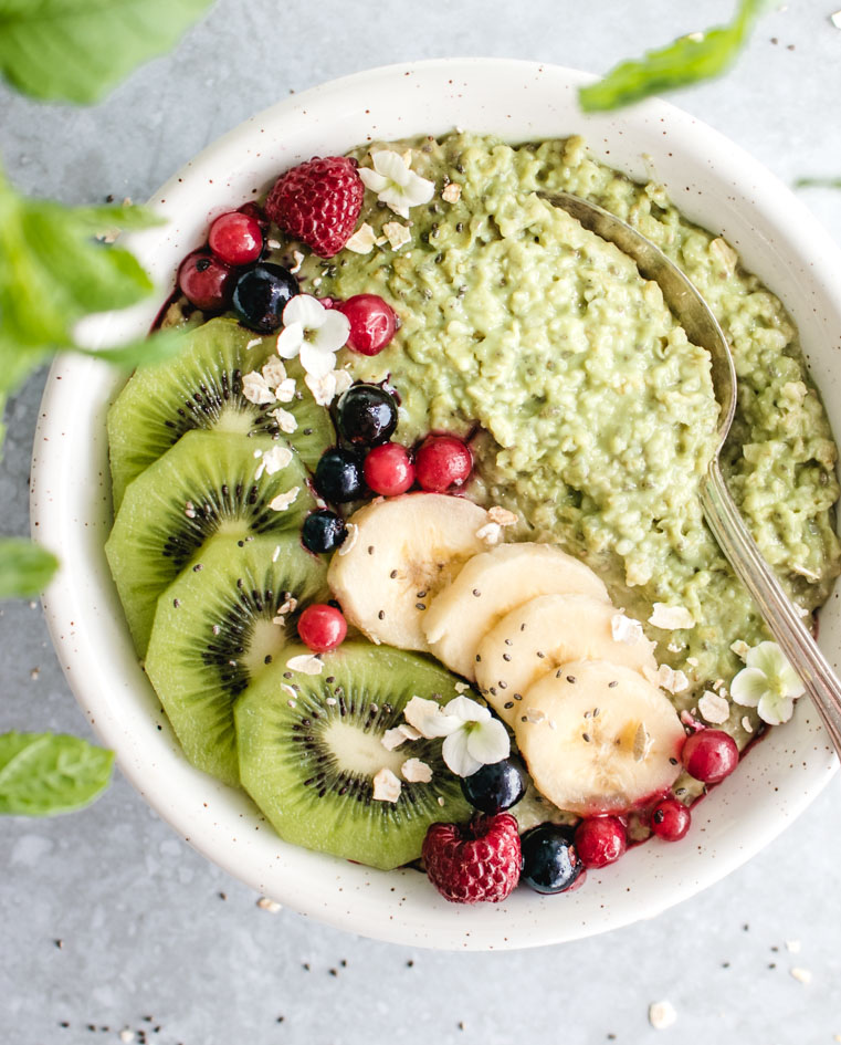 Matcha oatmeal served in a bowl topped with banana and berries.