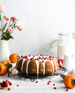 Vegan Persimmon Cake topped with a glaze and topped with Pomegranate seeds.