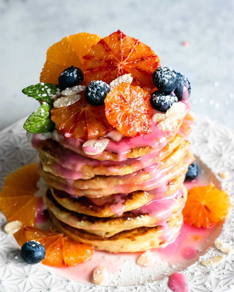 Blood Orange Vegan Pancakes topped with orange slices, yoghurt and blueberries.