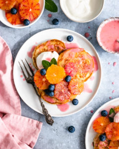 Blood Orange Vegan Pancakes topped with orange slices, yoghurt and blueberries.