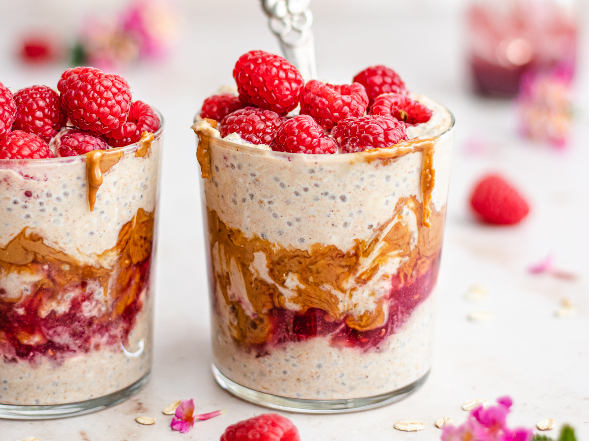 Peanut butter and jelly overnight oats with swirls of peanut butter and fresh raspberries