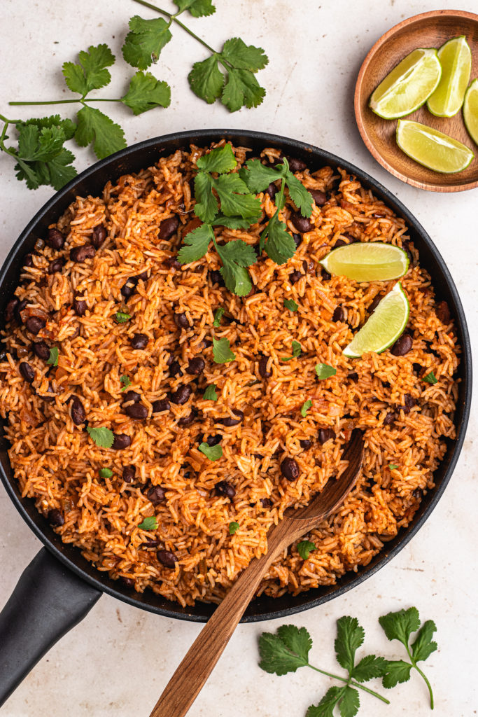 Vegan Mexican rice and black beans in a pan garnished with cilantro and lime 