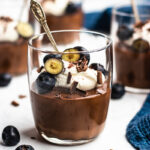 Almond milk Chocolate Pudding served in glasses topped with cream, berries and chocolate.