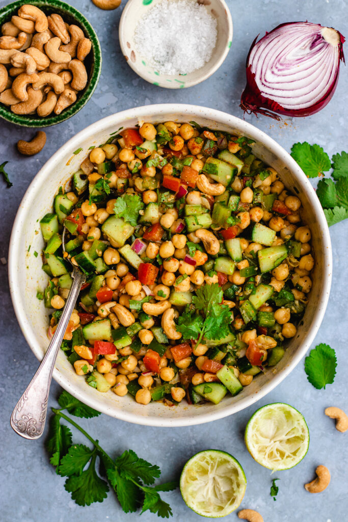 Indian chickpea salad served in a white bowl with a big spoon.