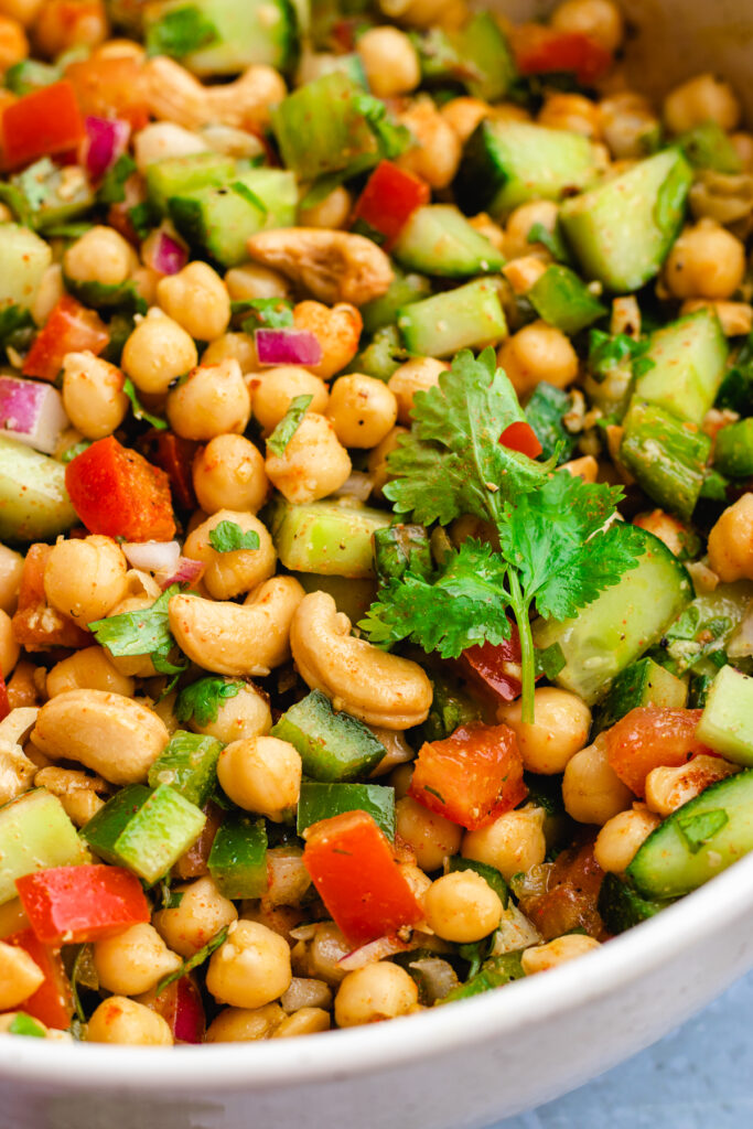 Closeup of the Indian chickpea salad served in a white bowl with a big spoon.