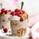 Protein chia pudding served in a glass with yoghurt, raspberries raspberries, granola and peanut butter.