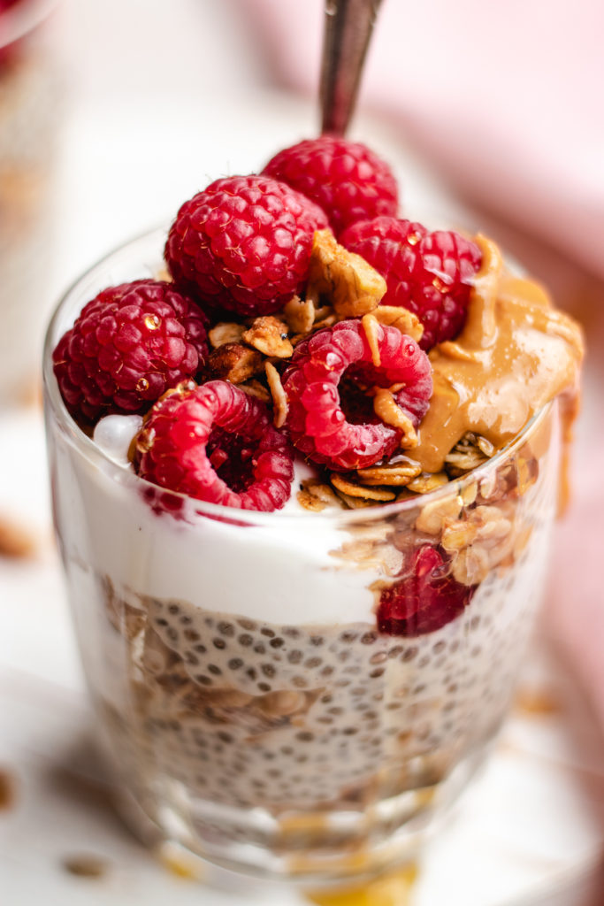Protein chia pudding topped with fresh raspberries, air fryer granola and a drizzle of peanut butter