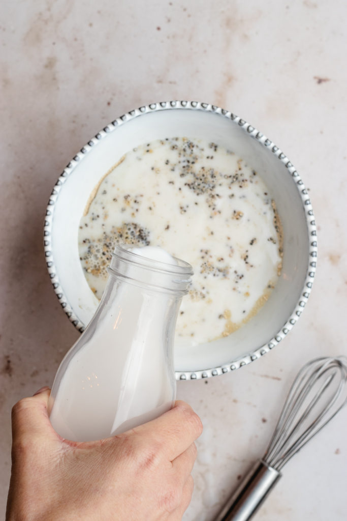Pouring in the milk to the bowl with the chia seeds and protein powder