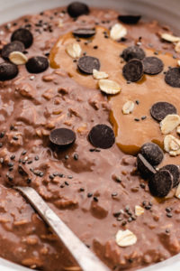 Closeup of these creamy chocolate Protein overnight oats served in a bowl topped with peanut butter and chocolate chips.