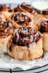 air fryer cinnamon roll topped with frosting.