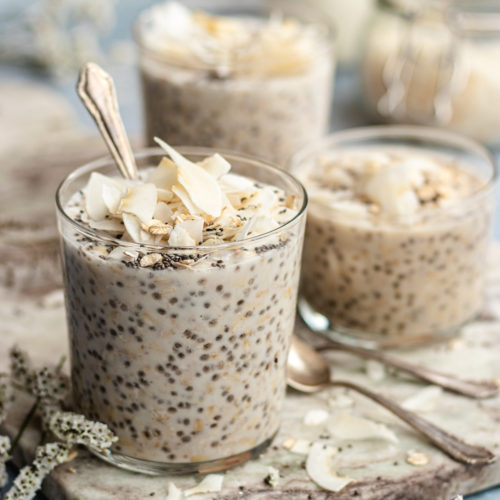 Three glasses filled with creamy coconut milk overnight oats topped with coconut