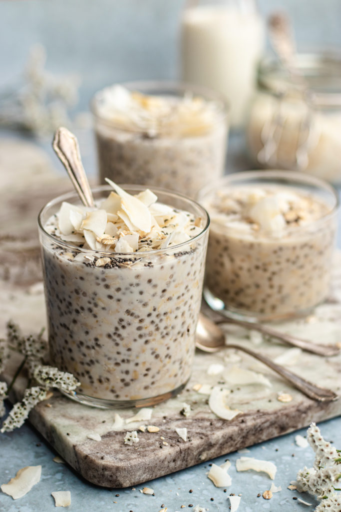 coconut milk overnight oats jars topped with coconut, oats and chia seeds.