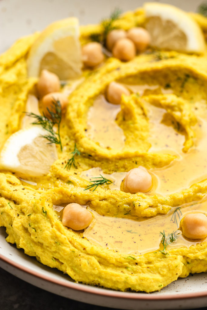 Lemon dill hummus topped with olive oil, dill and fresh lemon slices.