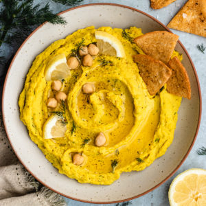 Lemon dill hummus served in a bowl with pita chips.