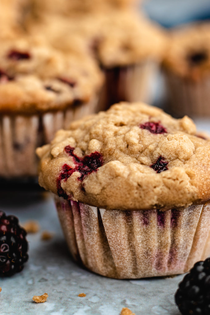 Closeup of a blackberry muffin with fresh blackberries next to it.