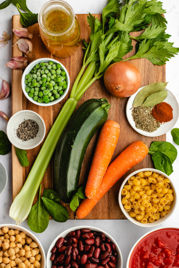 All the ingredients needed to make this vegan Minestrone Soup presented on a cutting board.