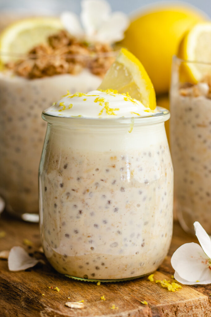 small glass filled with overnight oats topped with yoghurt and lemon.