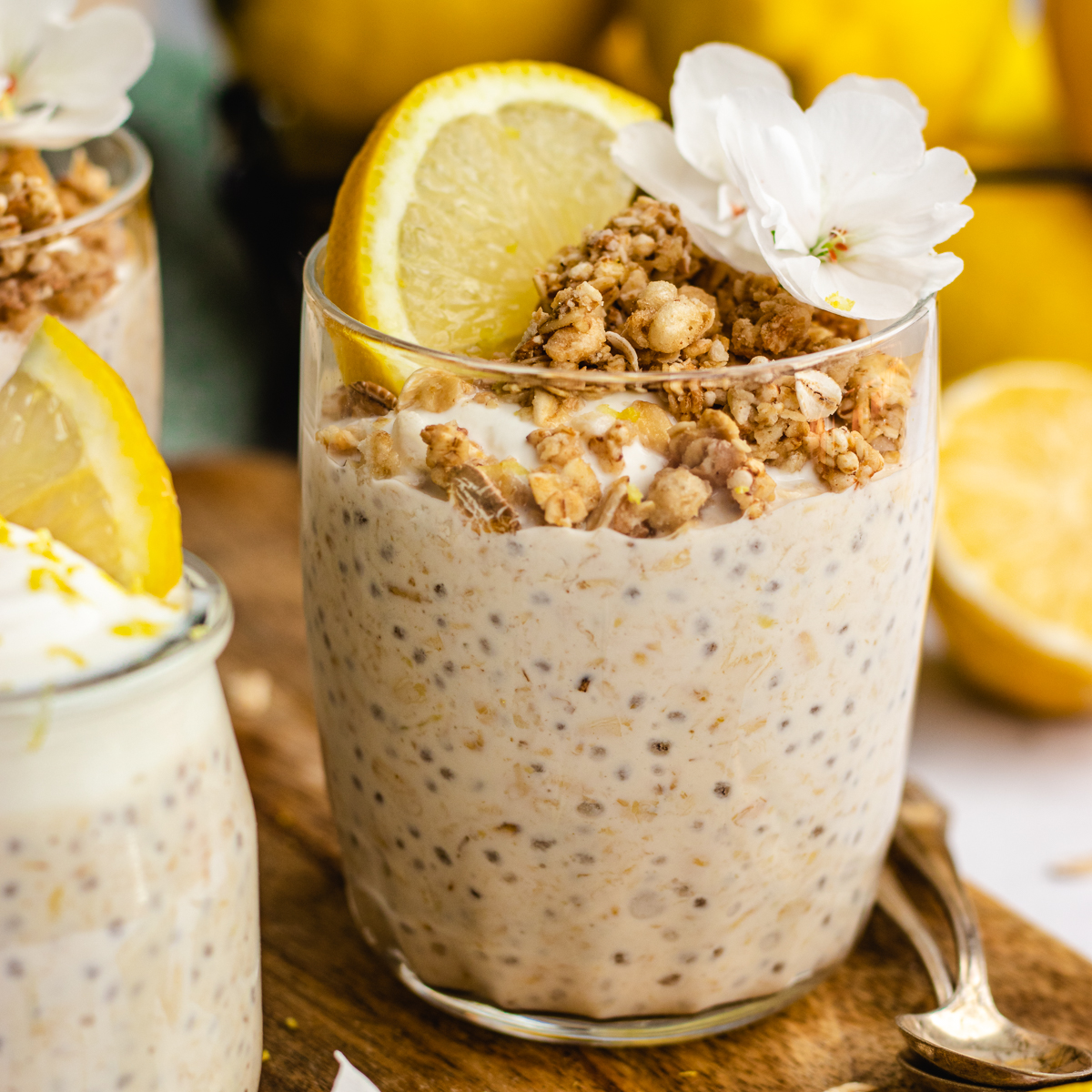 Lemon cheesecake overnight oats served in a glass topped with yoghurt, granola and lemon.