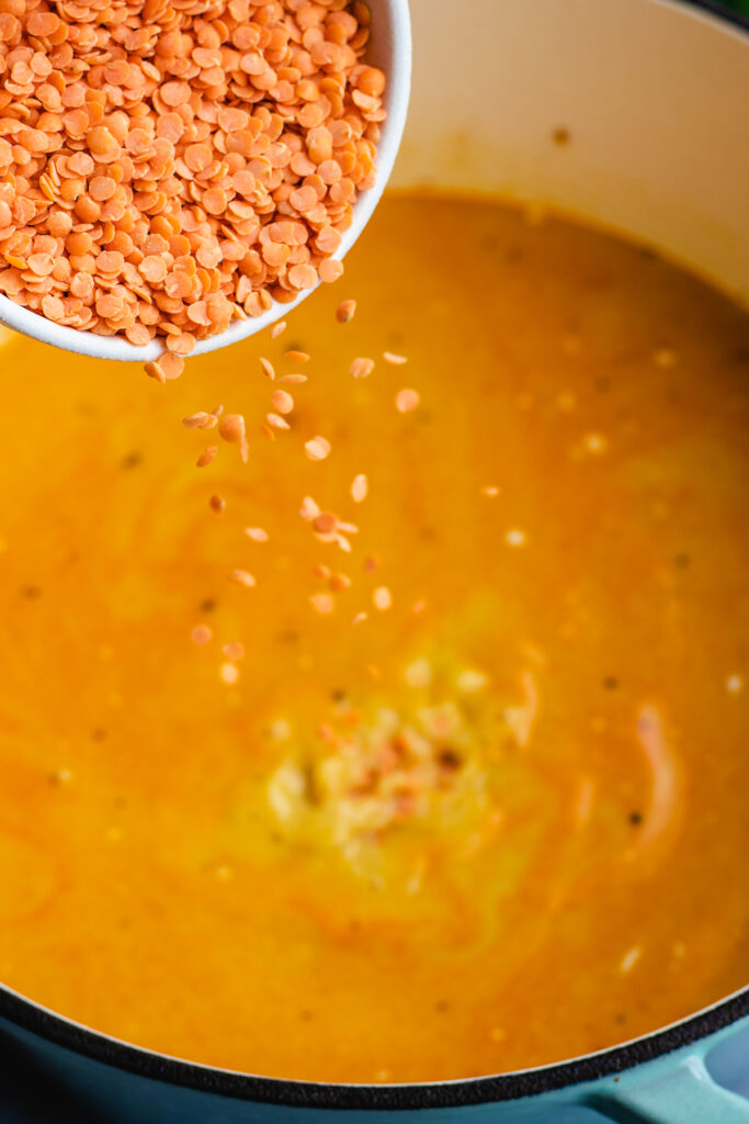 Step by step photo, pouring in the red lentils into the pot. 