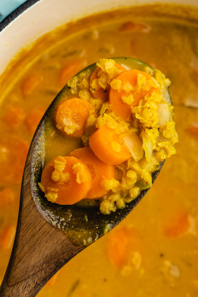 The Cooked carrots and lentils on a wooden spoon.