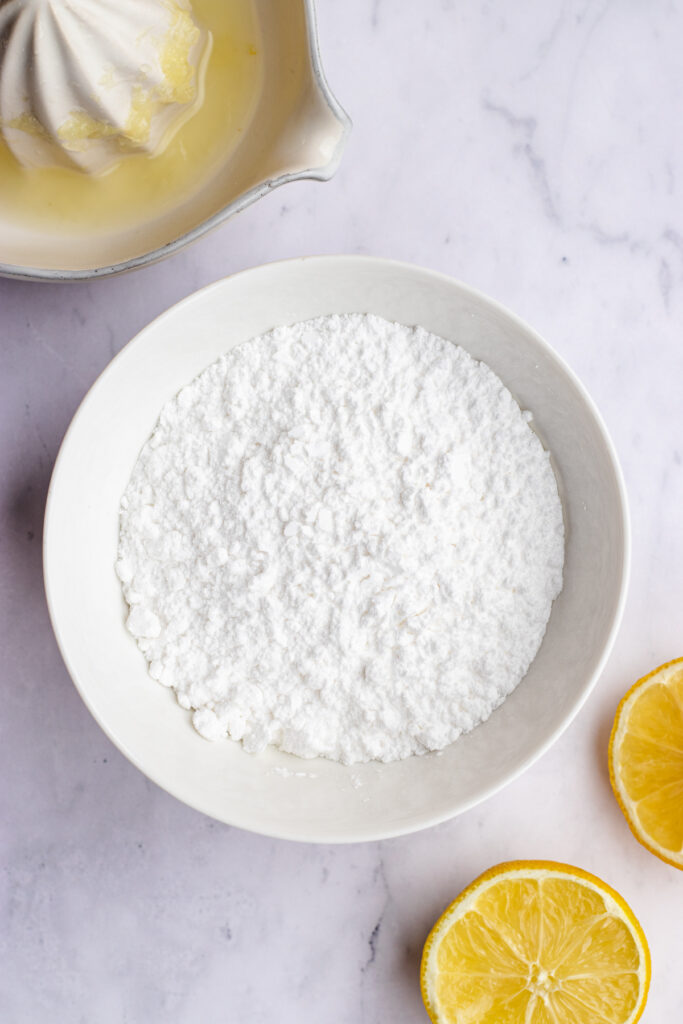 Instructional photo, a bowl of powdered sugar and lemons.