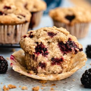 Vegan blackberry muffins with streusel topping cut in half to show the inside.