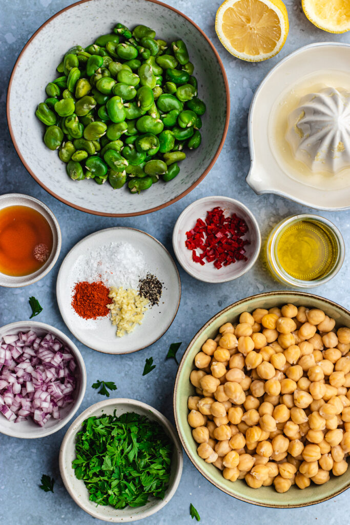 All the ingredients to make this Fava bean chickpea salad presented in small bowls. 