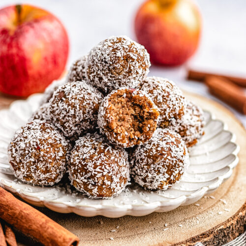 A stack of Apple Pie Bliss Balls on a small plate with one cut in half to show the inside.