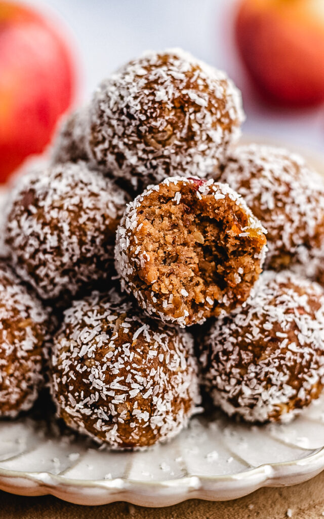 A stack of Apple Pie Bliss Balls on a small plate with one cut in half to show the inside.