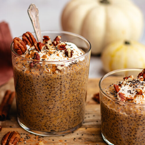 Pumpkin Chia Pudding in a glass topped with some yoghurt, cinnamon and pecans.
