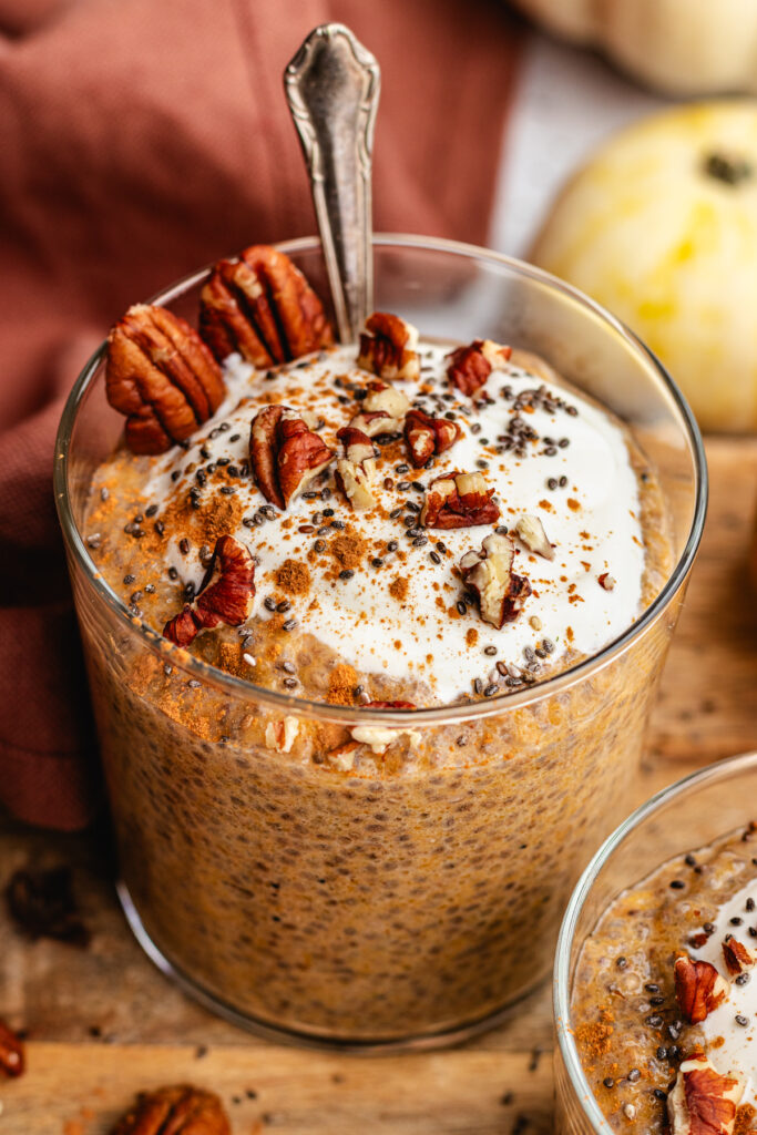 Pumpkin Chia Pudding in a glass topped with some yoghurt, cinnamon and pecans.