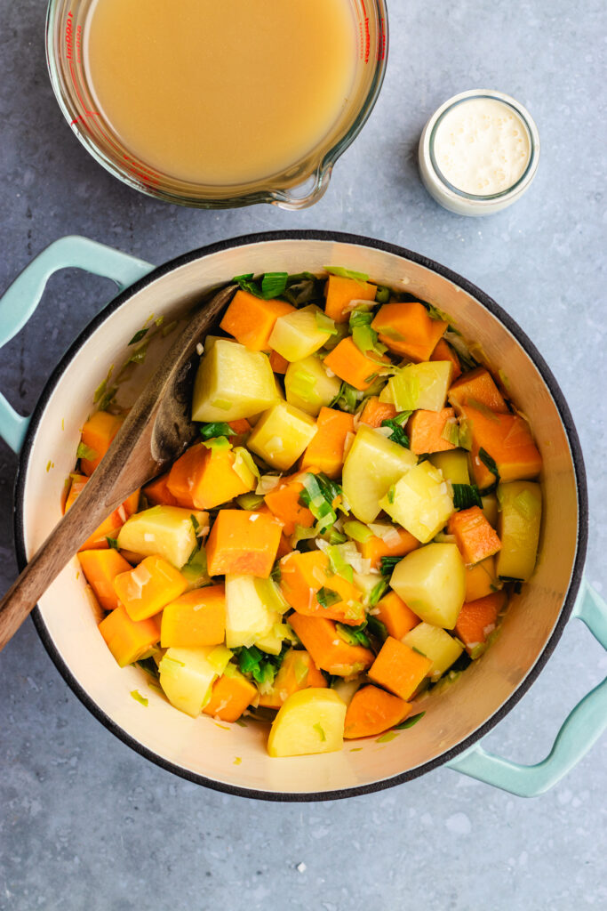 The sautéed potatoes and pumpkin in a large pot.