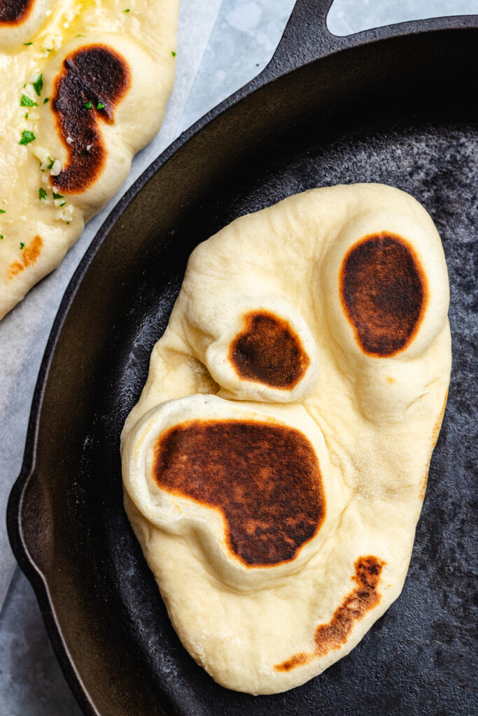 The cooked naan bread in a frying pan. 
