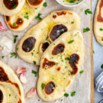 Vegan Naan Bread topped with butter, garlic and parsley.