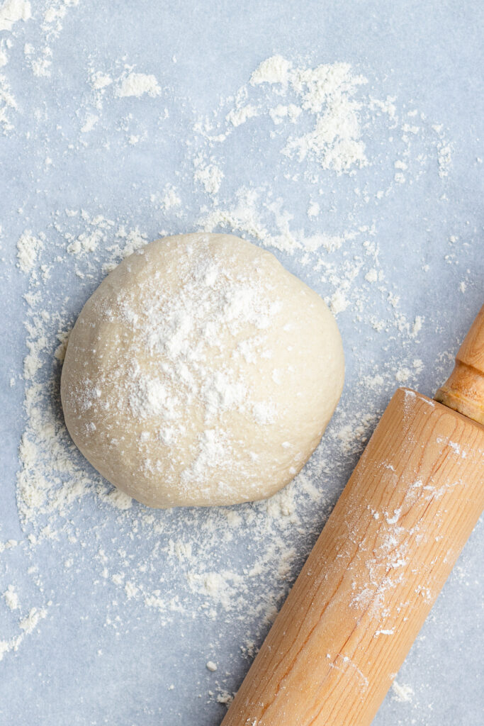 The dough on a floured surface with a rolling pin.