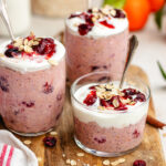 Cranberry overnight oats served in 3 glasses topped with yoghurt and cranberry sauce.