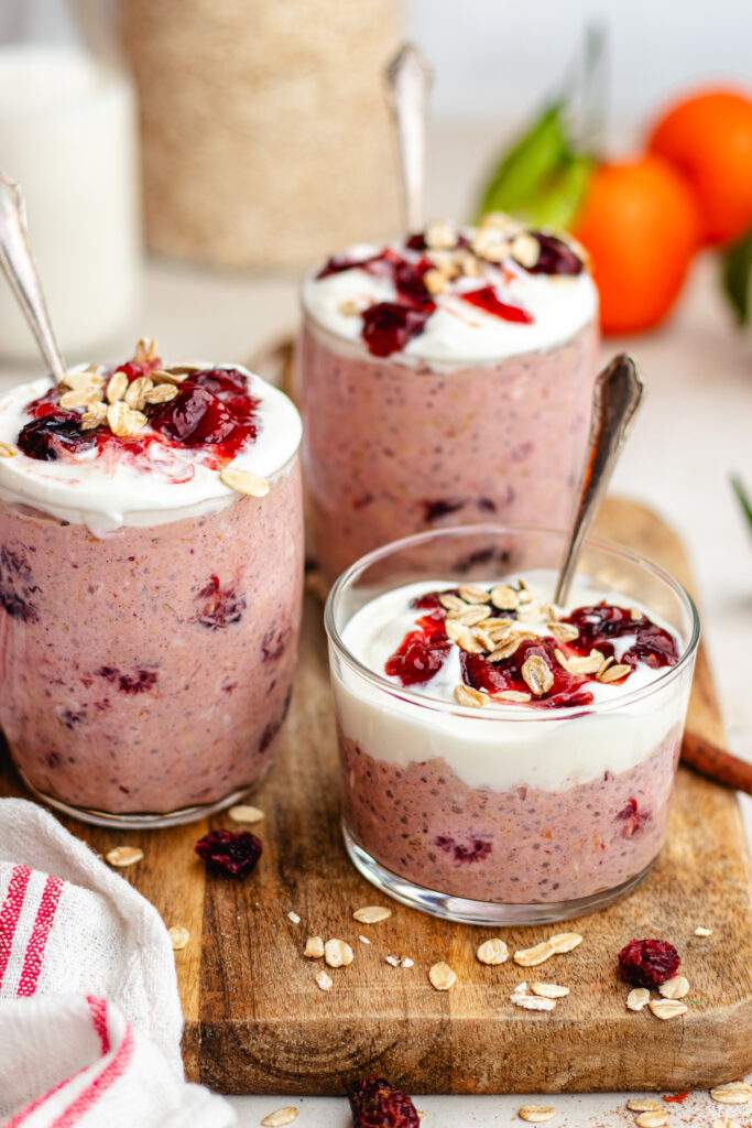 Cranberry overnight oats  served in 3 glasses topped with yoghurt and cranberry sauce.