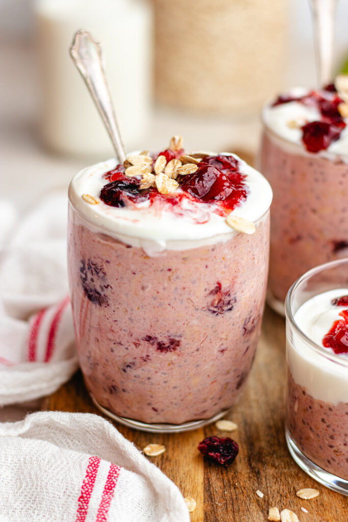 Cranberry overnight oats served in 3 glasses topped with yoghurt and cranberry sauce.