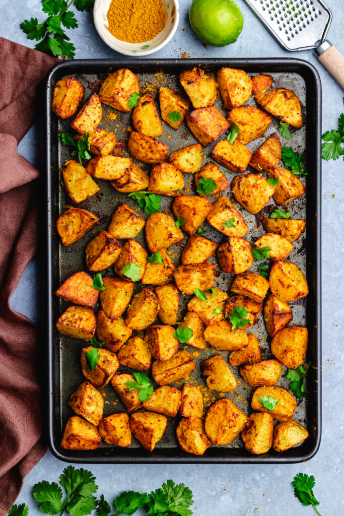 The baked potatoes on a baking tray topped with cilantro.
