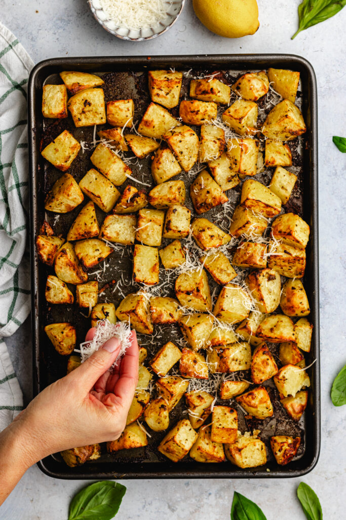 Topping the roasted potatoes with grated parmesan. 