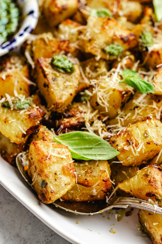 Closeup of these Pesto roasted potatoes topped with parmesan cheese and fresh basil. 